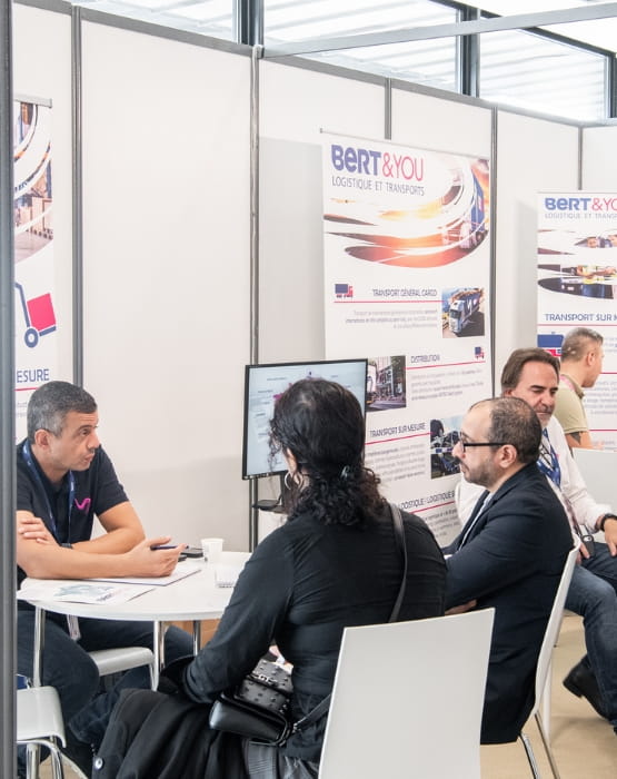 Participants exchanging ideas at exhibition stands at Top Transport Europe.